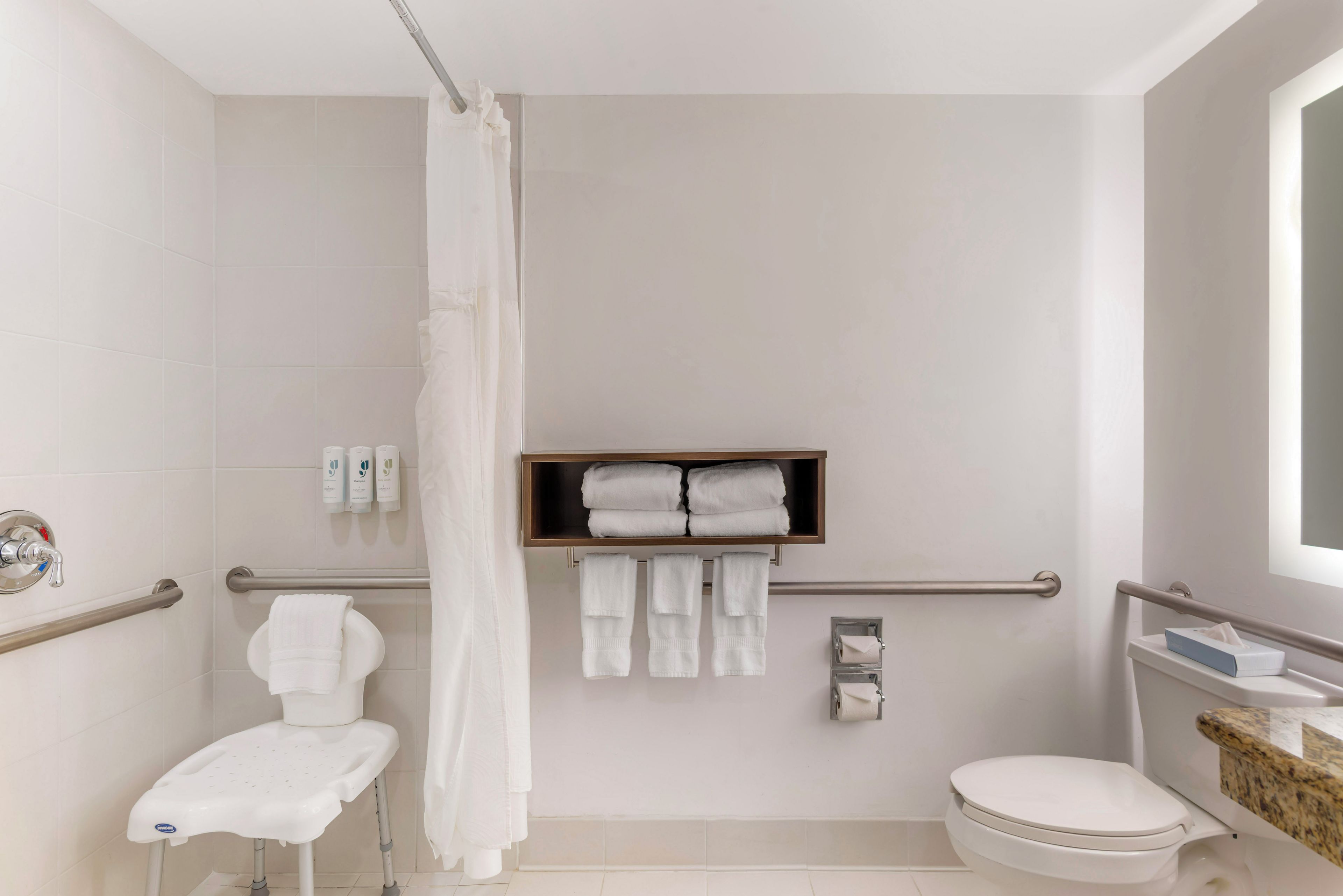 Un baño moderno con ducha, inodoro y repisa con toallas.