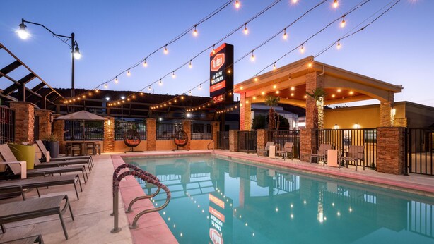 Un espace piscine avec des chaises longues, un coin salon abrité et un panneau indiquant « Anten by Best Western ».