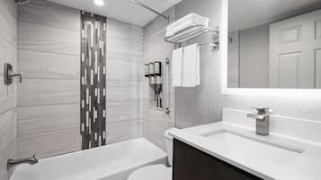 A modern bathroom with a bathtub, toilet, and shower.