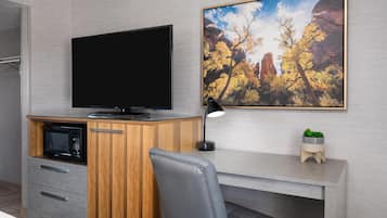 Una cocina moderna con microondas integrado, un armario de madera, un televisor de pantalla plana y un escritorio con una silla.