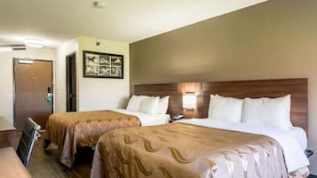 Una habitación de hotel con dos camas, un escritorio y una puerta.