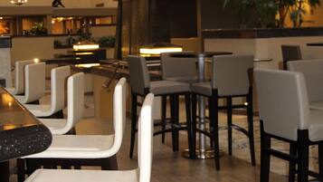 Un moderno vestíbulo de hotel con varias zonas de restauración, detalles de madera y un bar central.