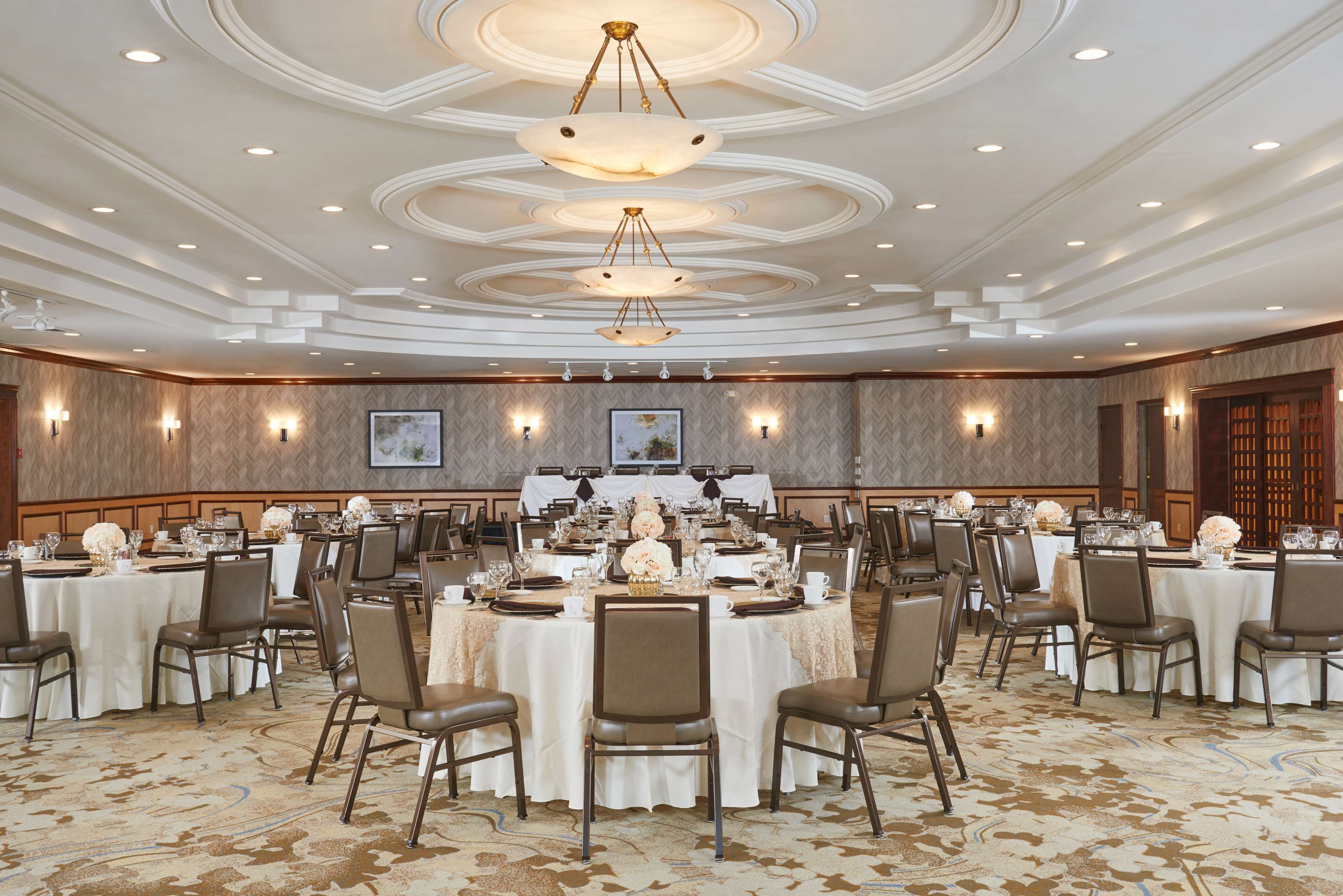 Un salón de banquetes con mesas redondas, sillas y candelabros.