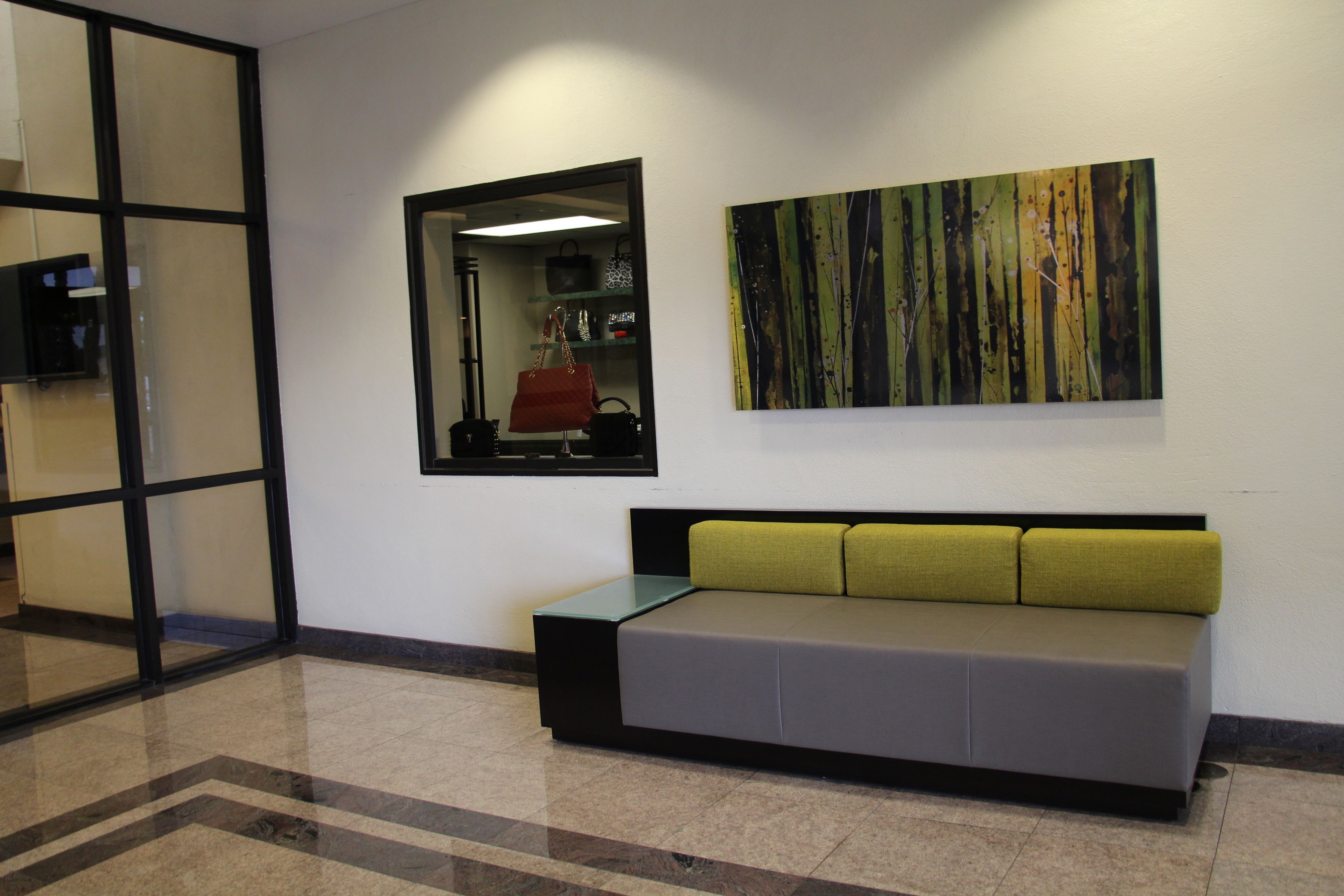 A reception area with a sofa, a mirror, and a painting on the wall.