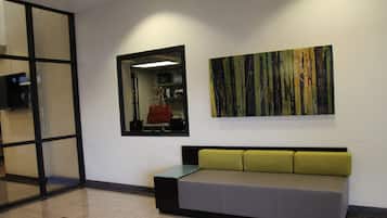 A reception area with a sofa, a mirror, and a painting on the wall.