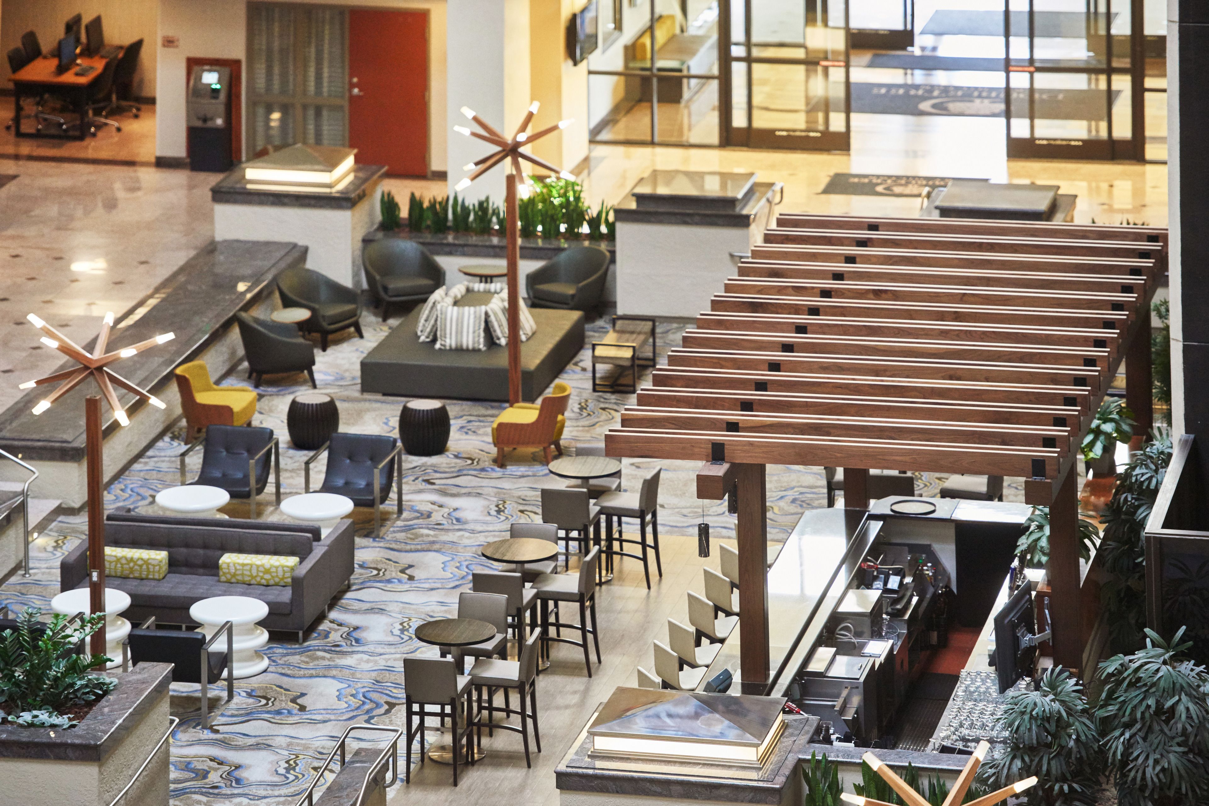 Eine geräumige Lobby mit einer modernen Sitzecke, einem Empfangsbereich und Blick ins Innere durch große Glastüren.