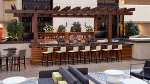 A bar area with multiple seating options, including bar stools and sofas, and a television screen. - DoubleTree by Hilton Fresno Convention Center (Fresno)