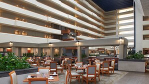 A multi-level hotel lobby with dining areas, seating arrangements, and a central water feature. - DoubleTree by Hilton Fresno Convention Center (Fresno)