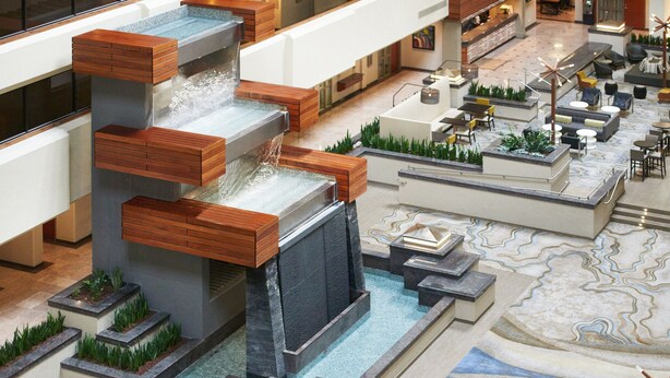 A modern lobby with a central water feature, seating areas, and a reception desk. - DoubleTree by Hilton Fresno Convention Center (Fresno)