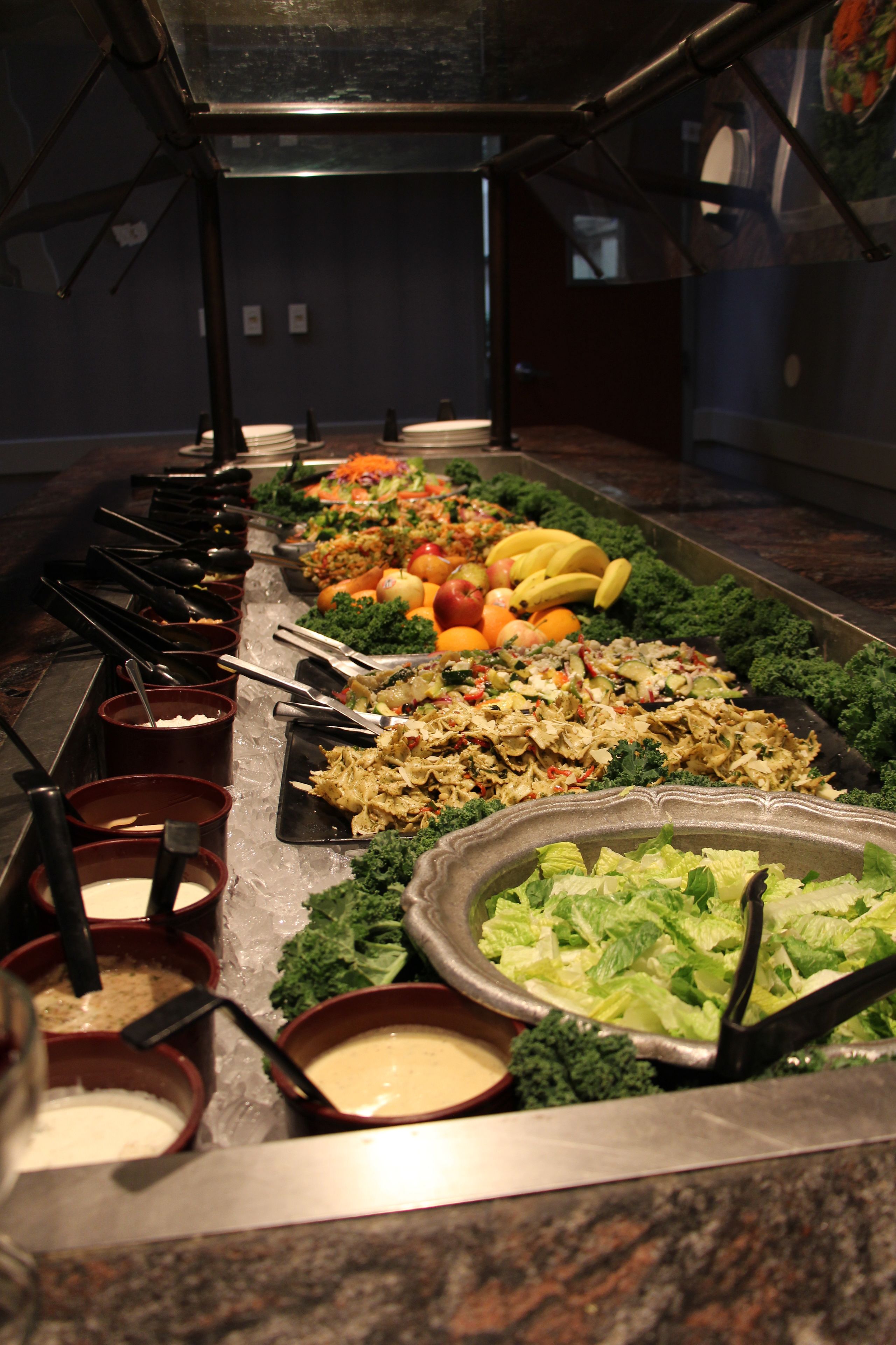 Un buffet proposant une variété de plats, notamment des salades, des fruits et des légumes.