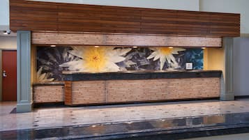Balcão de recepção com design em painel de madeira e um mural floral.