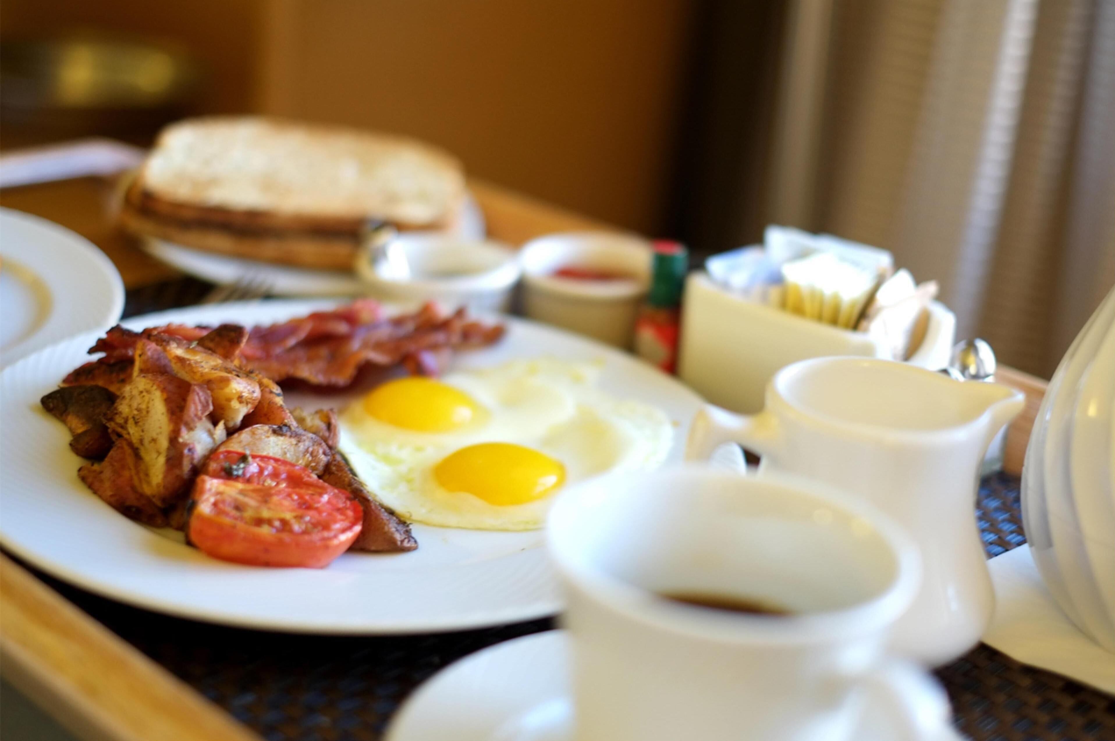 Un plato de desayuno con tocino, huevos y tomates.