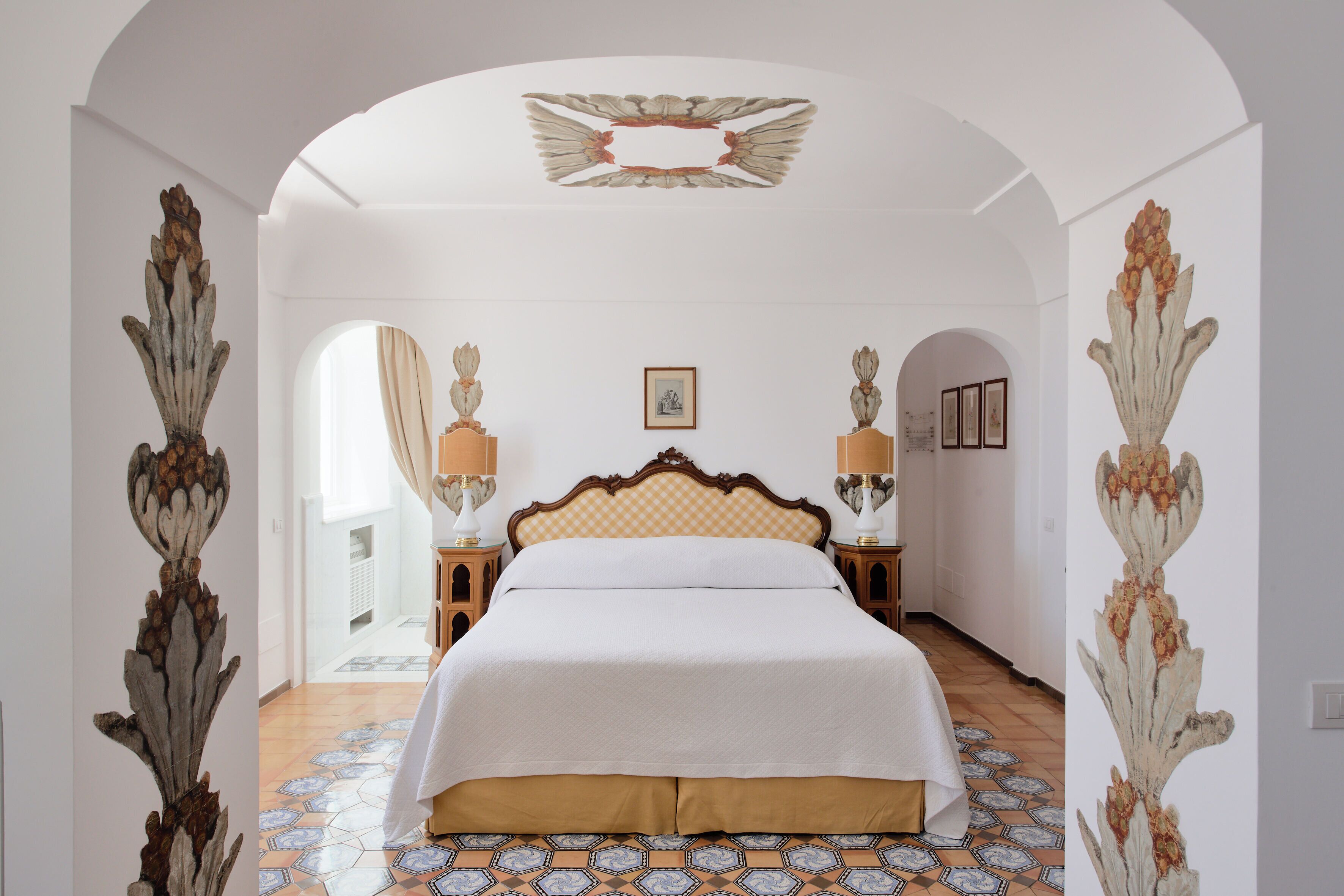 Une chambre spacieuse avec un grand lit, une tête de lit décorative et un plafond orné.