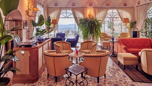 A hotel lobby with a bar, seating area, and large windows offering a view of the sea. - Le Sirenuse (Positano)