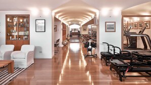 A spacious room with a wooden floor, a large bookshelf, exercise equipment, and a treadmill.