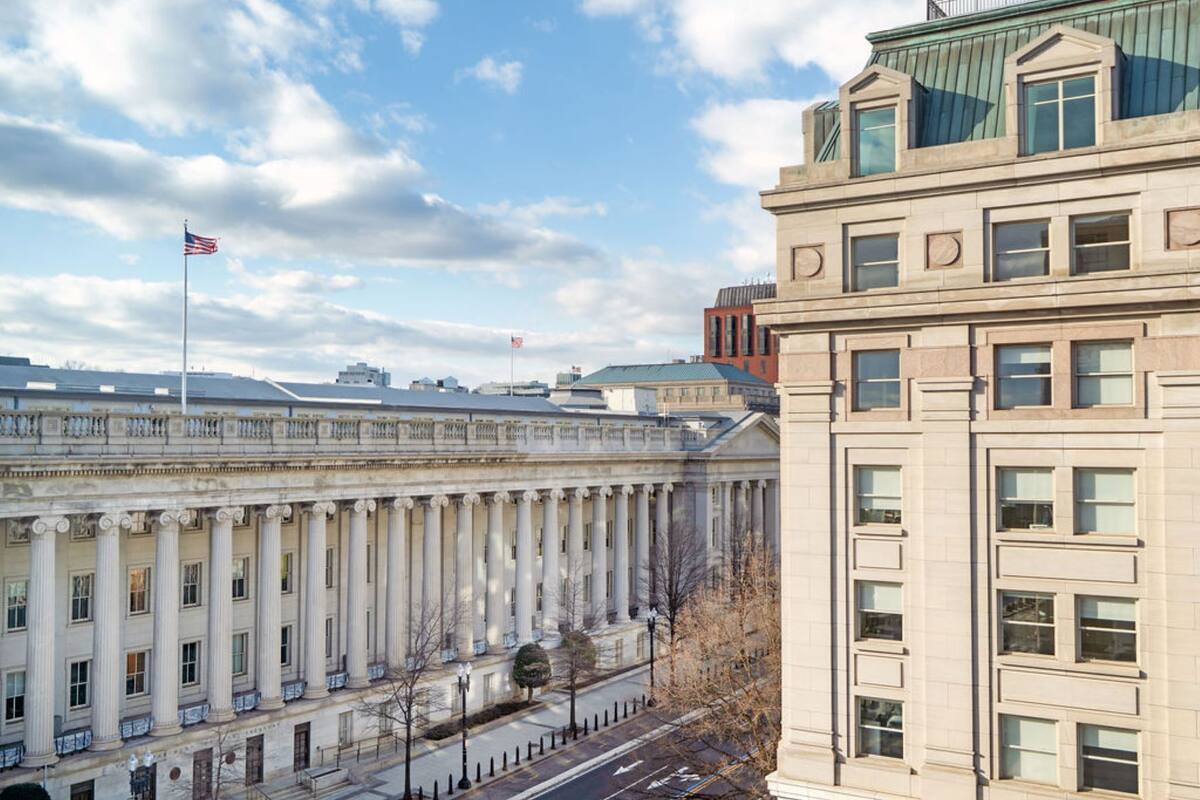 A large building with classical architecture, featuring a row of columns and a flag on top.
