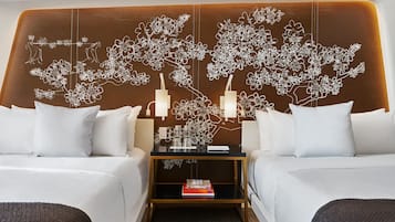 Habitación de hotel con dos camas, una mesita de noche con lámpara y un adorno de pared con motivos florales.
