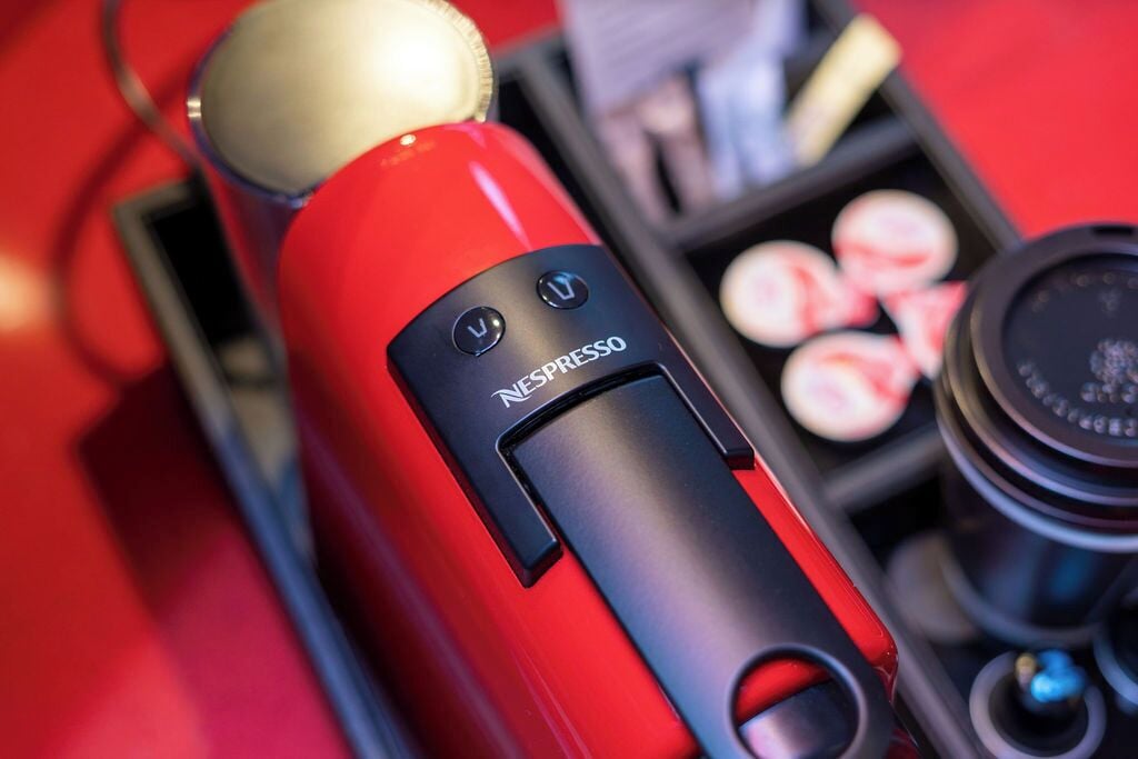 Punainen Nespresso-kahvinkeitin, jossa on vesisäiliö ja kahvikapselit.