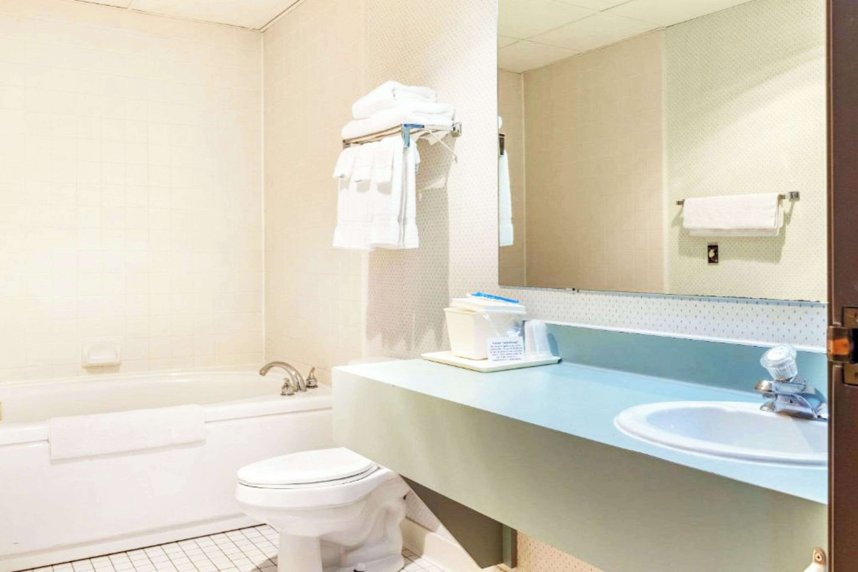 A bathroom with a bathtub, toilet, sink, and a towel rack with folded towels.