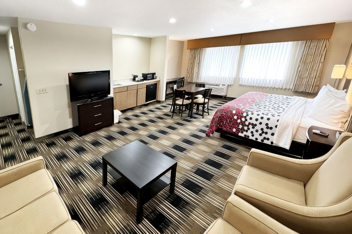 A hotel room with a bed, a desk, a television, and a sofa.