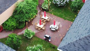 An outdoor patio area with tables and chairs, surrounded by greenery and decorative lights. -  Econo Lodge Wausau - Rothschild (Rothschild)