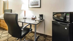 Une chambre d’hôtel équipée d’un bureau, d’une chaise, d’une lampe, d’une machine à café, d’un four à micro-ondes et d’un tableau encadré au mur.