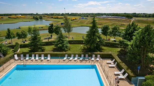 Piscina con tumbonas y vistas a un campo de golf y cuerpos de agua.