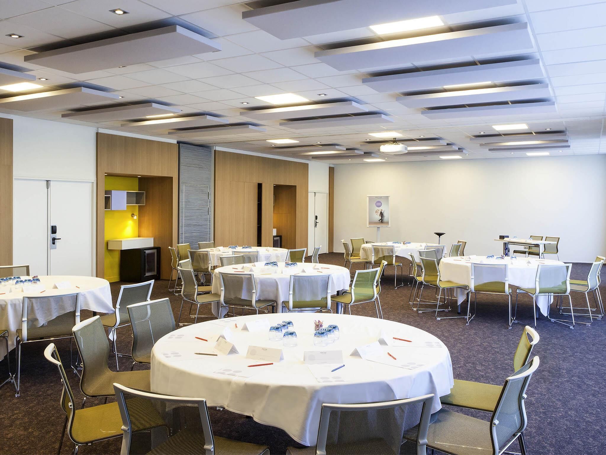 A conference room with round tables, chairs, and a whiteboard.