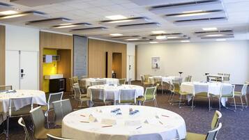 Une salle de conférence équipée de tables rondes, de chaises et d’un tableau blanc.