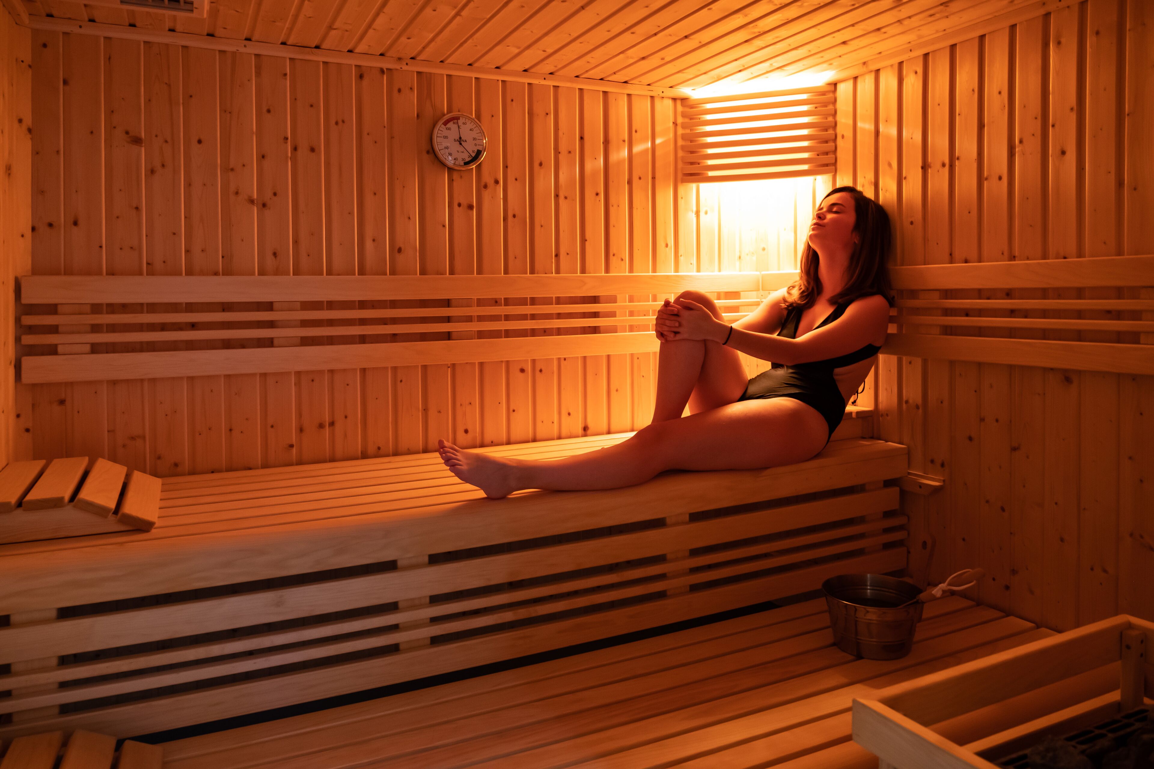 Una sauna con bancos de madera y un reloj en la pared.