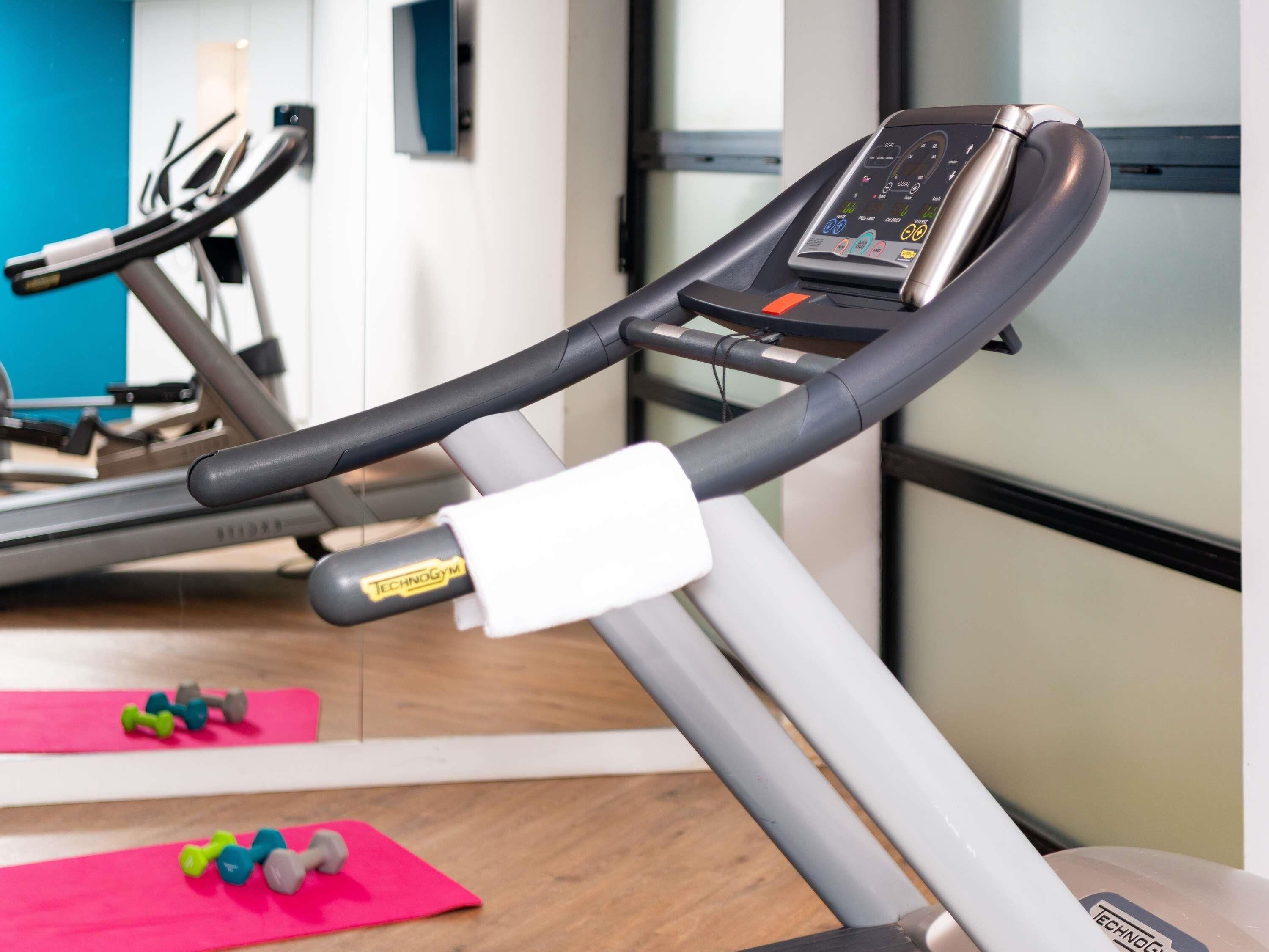 A gym with exercise equipment, including a treadmill and dumbbells.