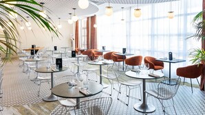 Un comedor moderno con mesas redondas, sillas de metal e iluminación colgante.