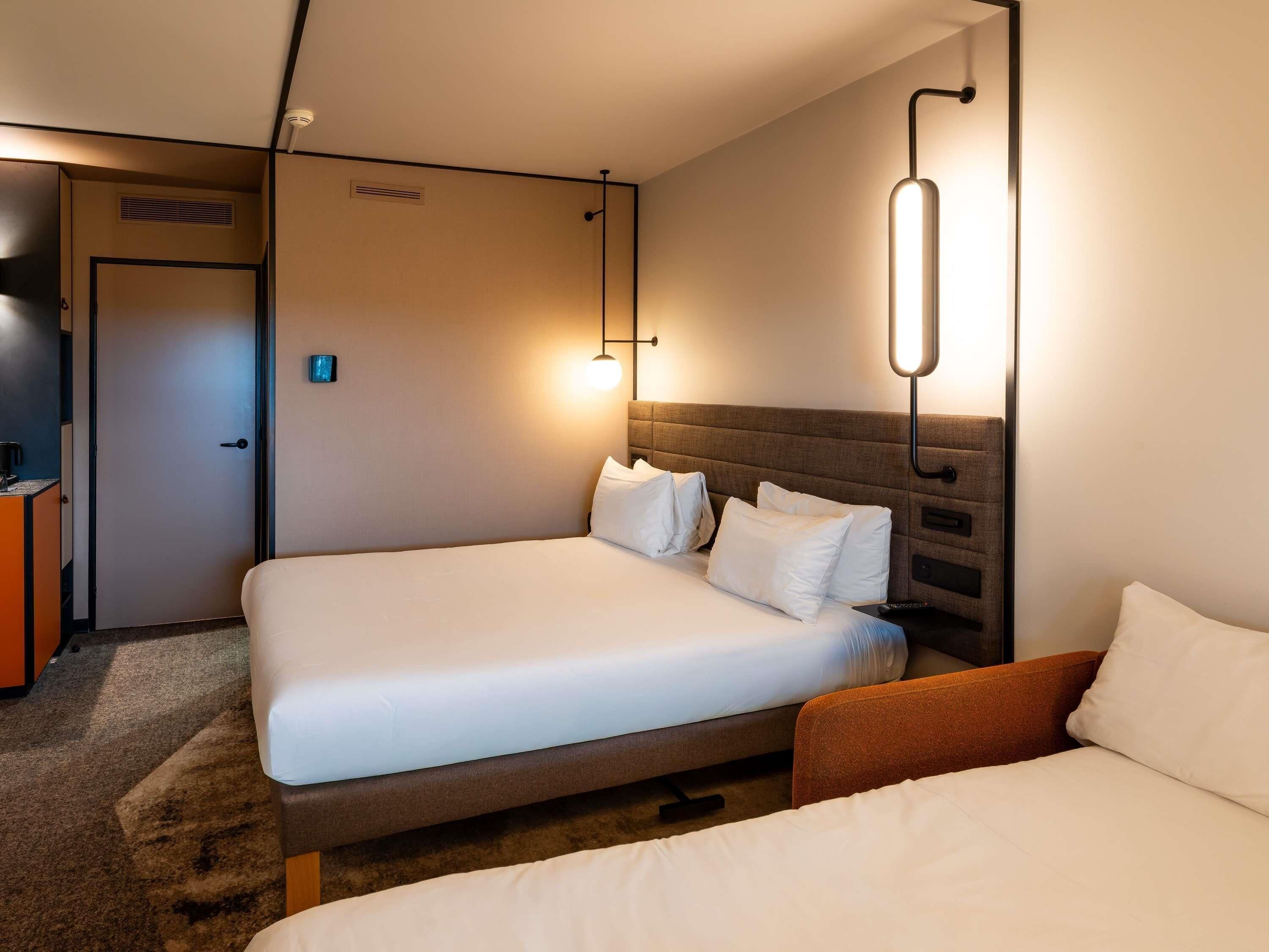 Ein Hotelzimmer mit zwei Betten, einem Schreibtisch und einem Fernseher.