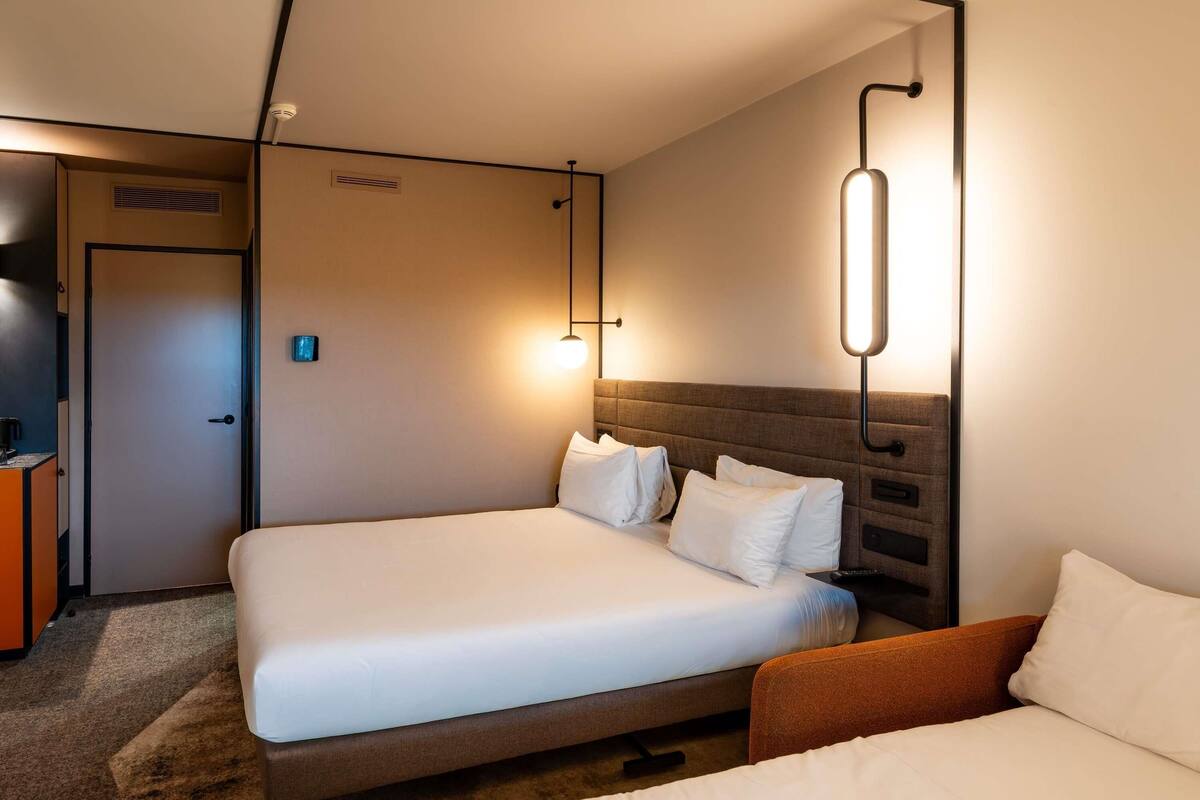A hotel room with two beds, a desk, and a TV.