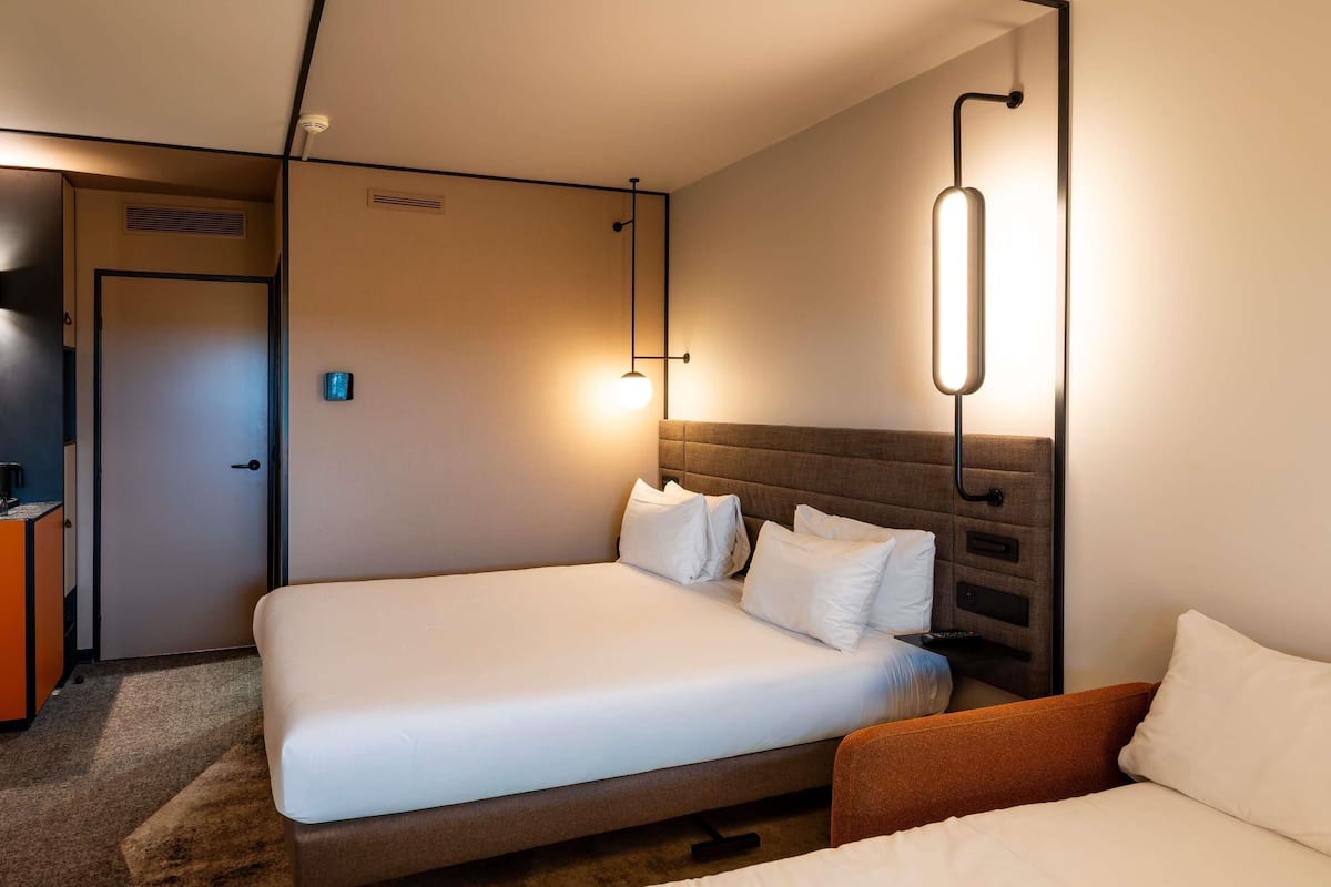 Une chambre d’hôtel avec deux lits, un bureau et une télévision.