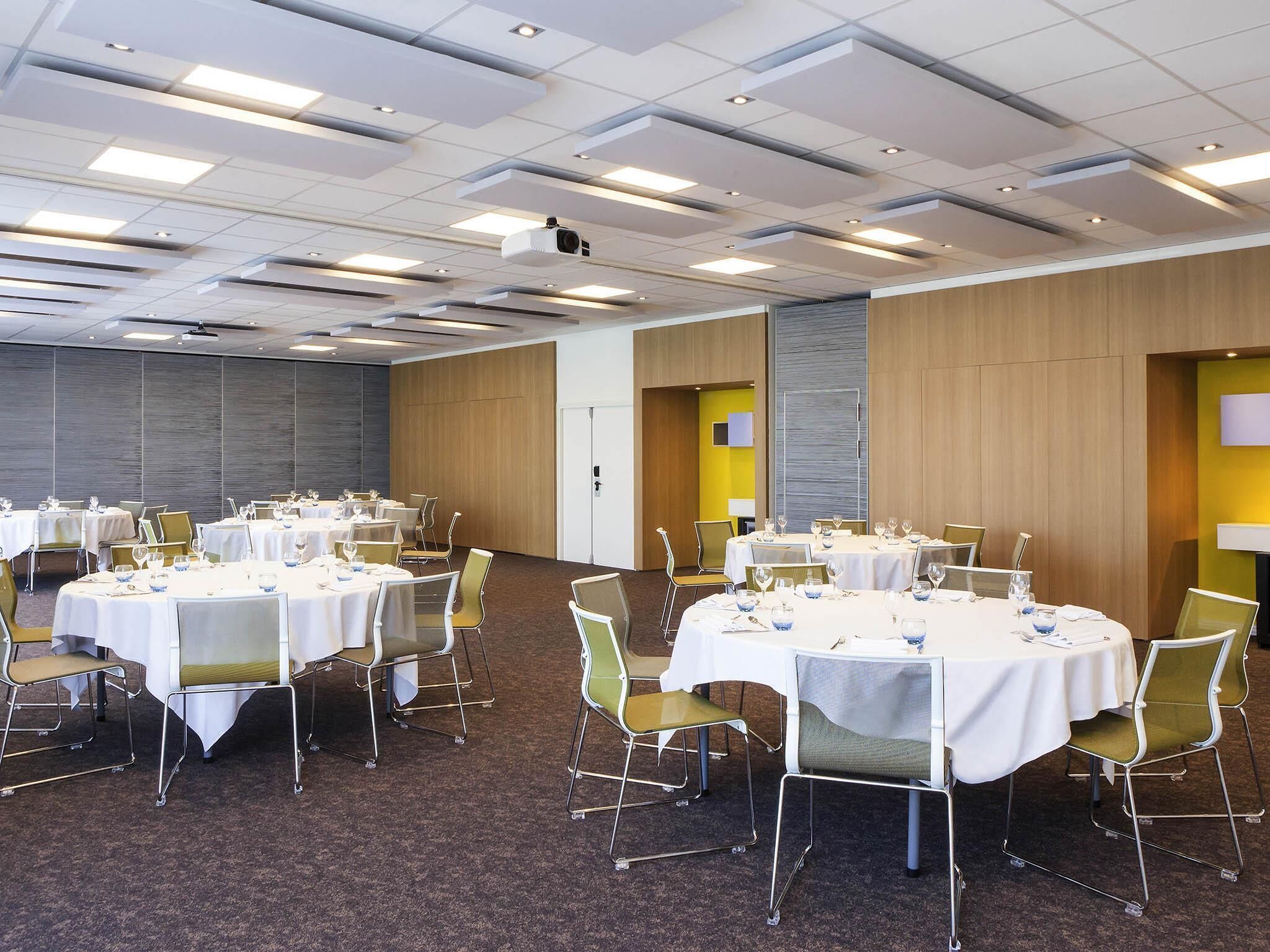 A conference room with round tables, chairs, and a projector.