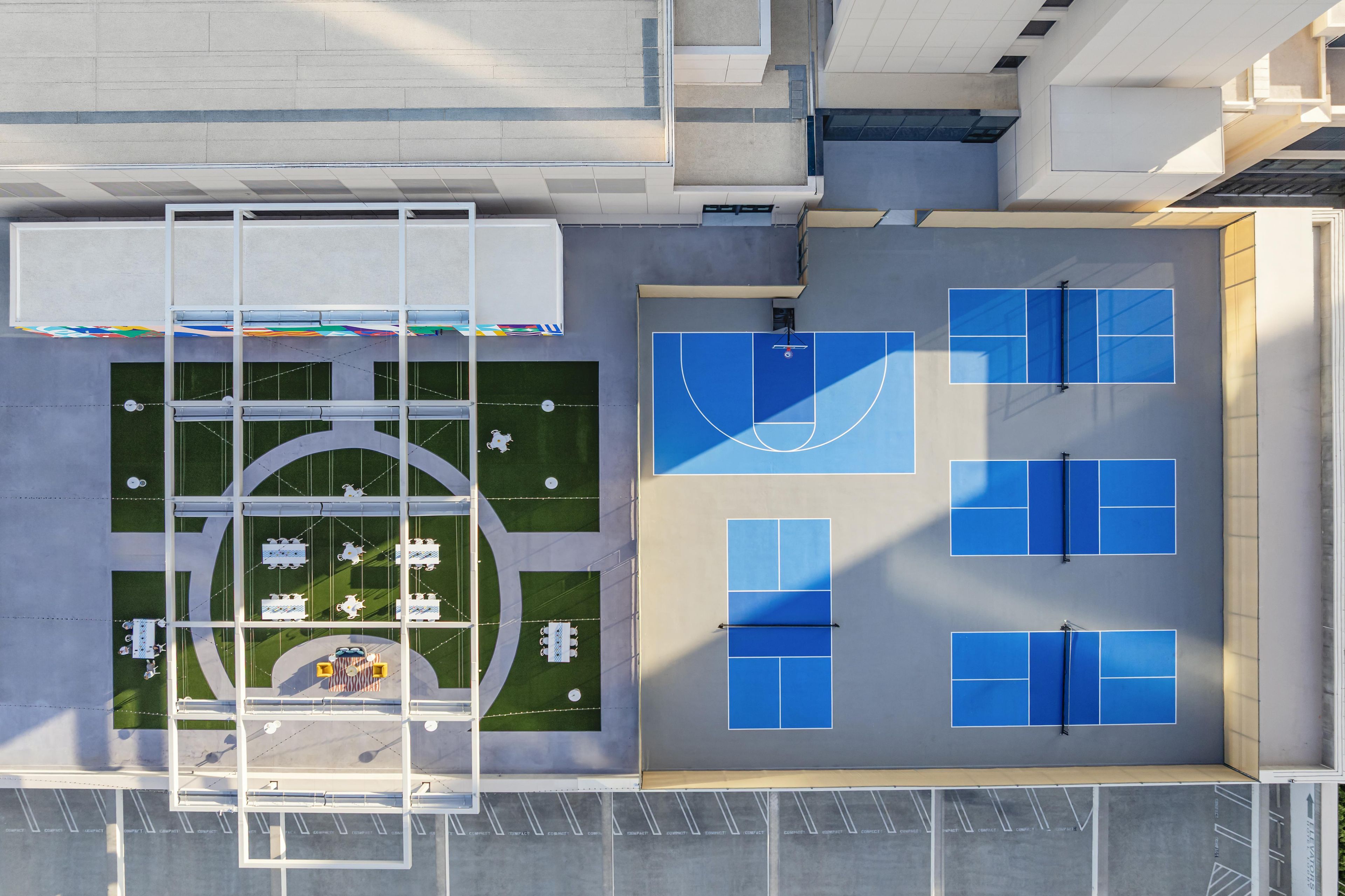 A rooftop with a basketball court, seating area, and a covered walkway.
