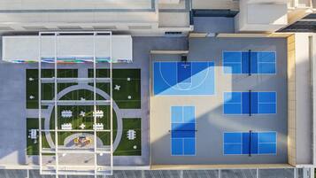 A rooftop with a basketball court, seating area, and a covered walkway.