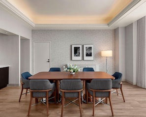 A conference room with a wooden table, six grey upholstered chairs, a white door, two framed pictures on the wall, and a floor lamp. - Manchester Grand Hyatt San Diego (San Diego)