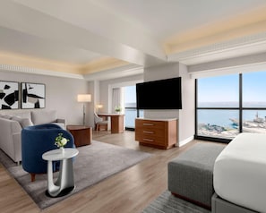 A modern hotel room with a large bed, a flat-screen TV, a desk, a sofa, and a view of the sea. - Manchester Grand Hyatt San Diego (San Diego)