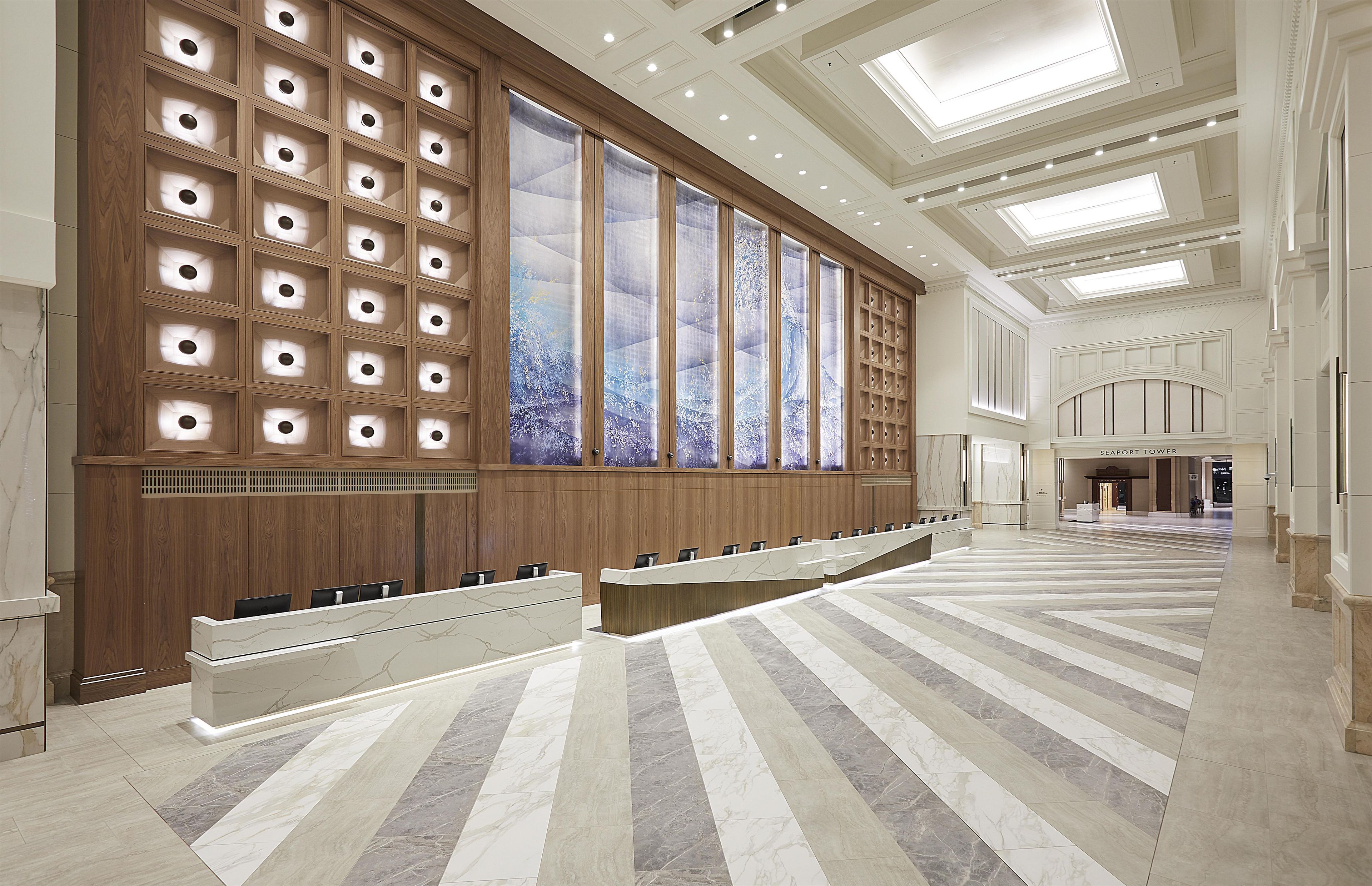 A spacious hotel lobby with a long reception desk, wooden paneling, and a large window with a view.