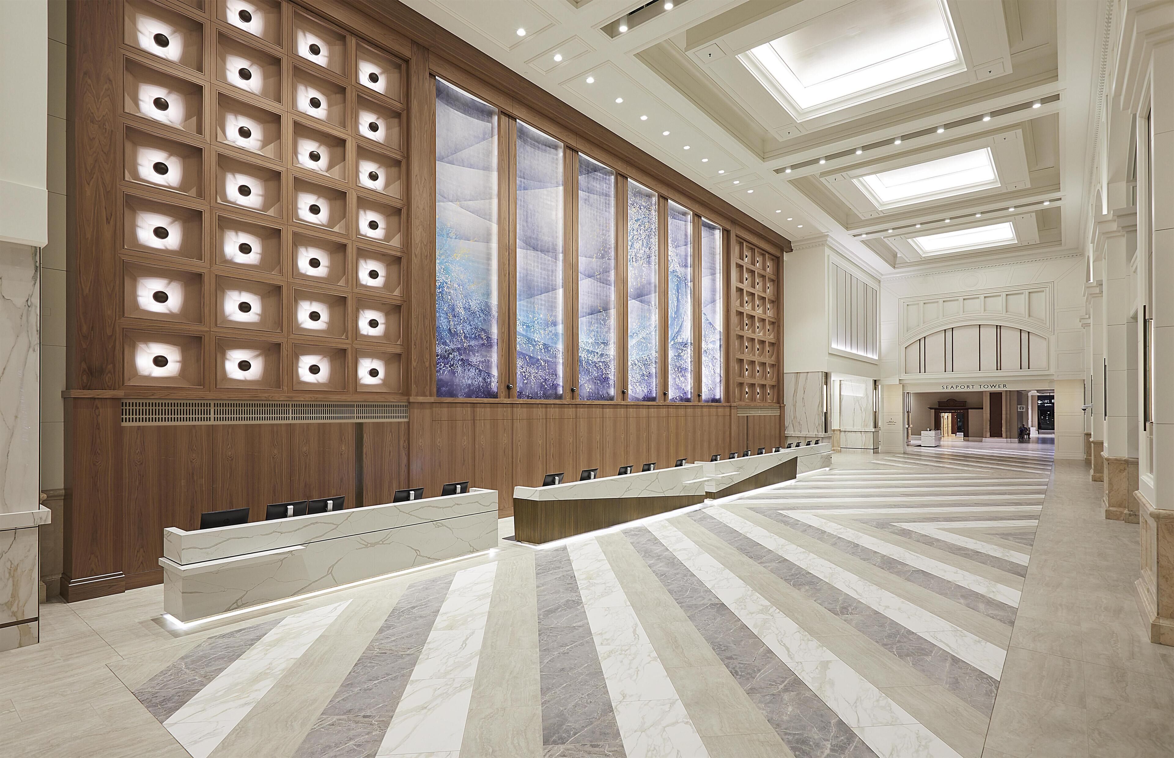 A spacious hotel lobby with a long reception desk, wooden paneling, and a large window with a view.