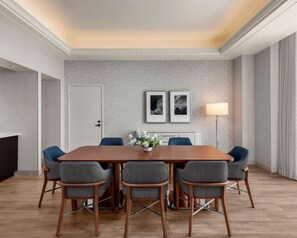 A conference room with a wooden table, six grey upholstered chairs, a white door, two framed pictures on the wall, and a floor lamp. - Manchester Grand Hyatt San Diego (San Diego)