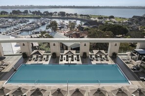 A pool with lounge chairs and umbrellas, a marina with boats, and a view of a cityscape across the water. - Manchester Grand Hyatt San Diego (San Diego)