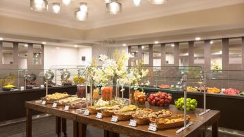 A buffet with various food items and a floral centerpiece.
