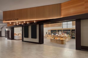 Un intérieur moderne avec un plafond en bois, un espace de vente bien visible portant le nom de « MARKET ONE », et un comptoir où sont exposés divers articles.