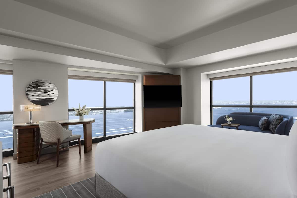 Ein modernes Hotelzimmer mit einem großen Bett, einem Schreibtisch mit Stuhl, einem Fernseher und einem Sofa.
