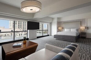 A hotel room with a large bed, a TV, a sofa, a coffee table, and a view of the cityscape. - Manchester Grand Hyatt San Diego (San Diego)