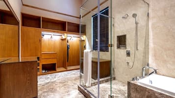A modern bathroom with a glass-enclosed shower, a wooden vanity, and a marble floor.