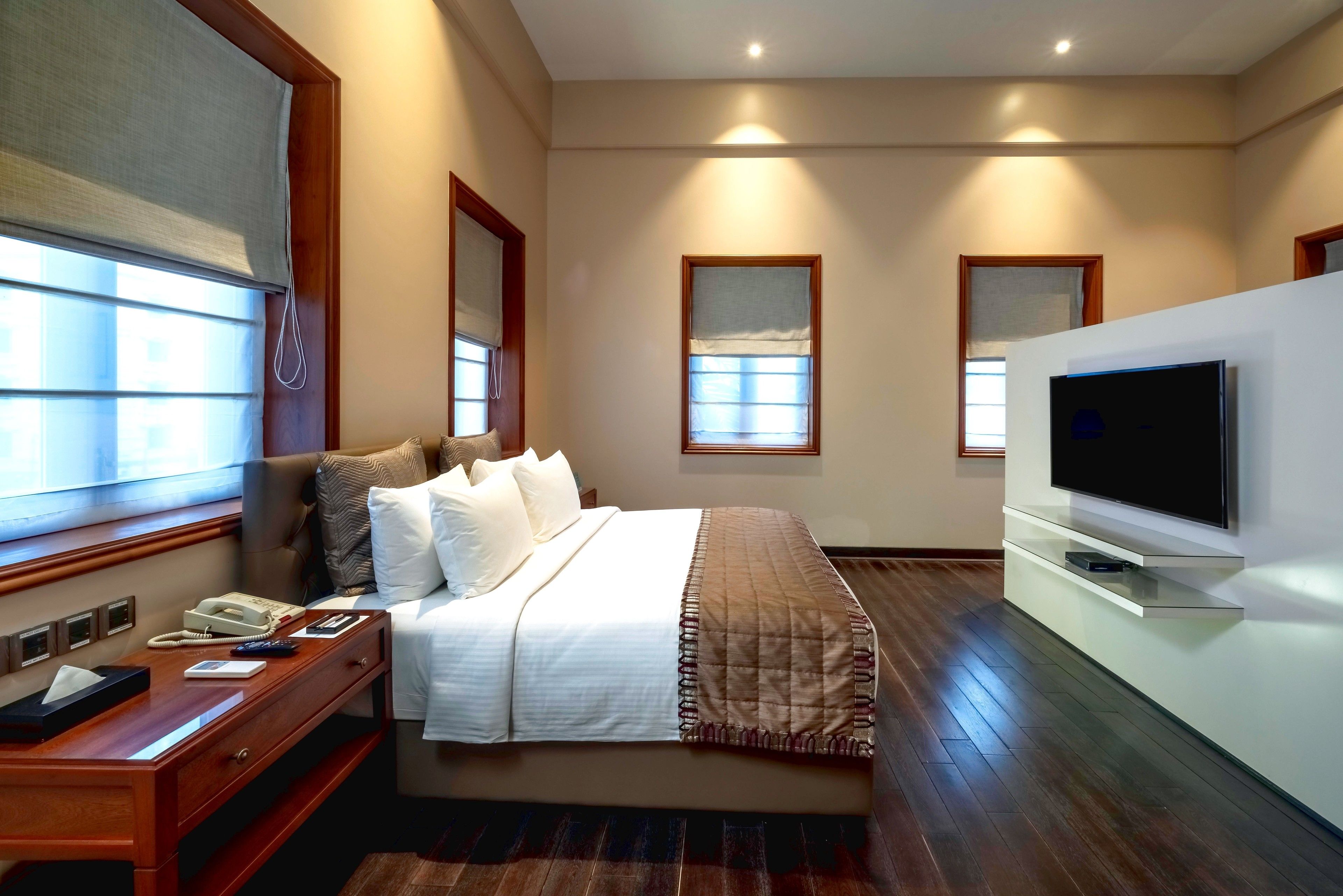 Une chambre d’hôtel avec un grand lit, un bureau avec un téléphone et un téléviseur à écran plat fixé au mur.